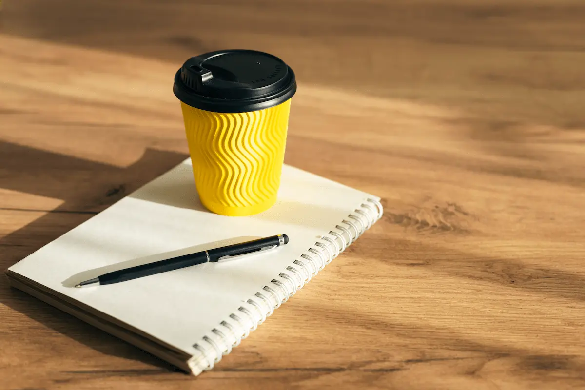 paper-cup-notepad-with-pen-wooden-table-copy-space material promocional utilizado después de un evento